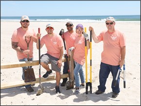 Employee volunteers build fence posts.